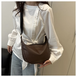 Brown faux leather crescent bag worn by model with adjustable strap detail