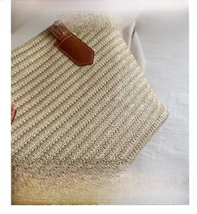 Macro view of woven straw bag texture and leather handle with white contrast stitching
