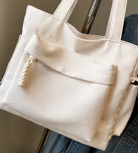 Vista laterale della borsa tote in tela beige con tasca frontale e dettaglio zip intrecciata