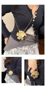 Detail van creatieve goudkleurige visvormige minitas met schubbenstructuur en metalen ketting