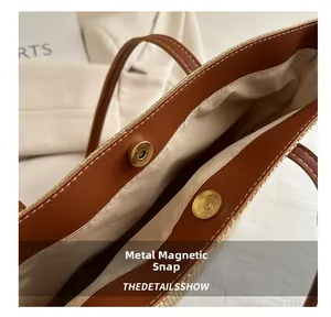 Detail of the magnetic buckle closure and brown leather trim on a woven tote bag