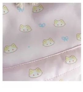 Dettaglio del tessuto in tela rosa con stampe di gatti e fiocchi e cuciture fini