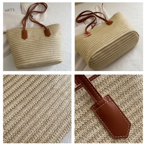 Detailed close-up of woven straw tote bag with brown leather handles and stitching