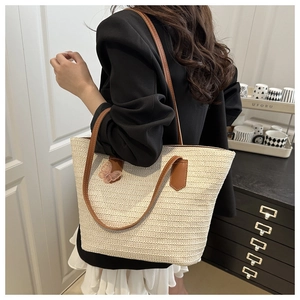 Detail of hand-woven straw tote with pink butterfly embroidery and brown leather straps