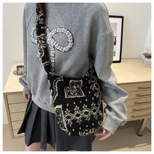 Détail du sac seau en peluche noire avec motif géométrique crème et bandoulière large