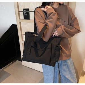 Dettaglio della borsa tote grande in tela nera con tasche laterali e cerniera