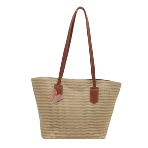 Large khaki straw tote bag with brown faux leather handles and pink mesh butterfly