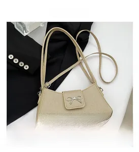 Detail of beige baguette bag showing diagonal fabric texture and silver bow buckle