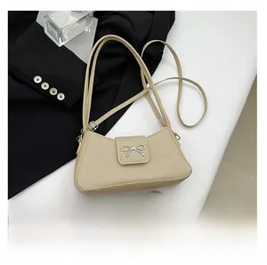 Close-up of beige woven baguette bag with a metal bow accent and daily essentials