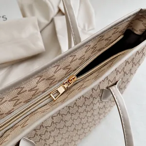 Detalle de cremallera metálica dorada y estampado de patrón M en bolso de cuero sintético