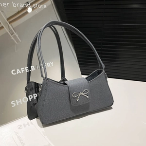 Elegant grey knitted baguette bag with silver metal bow clasp on a white display stand