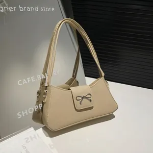 Retro beige baguette bag with ribbed texture, silver bow accent, and underarm shoulder straps