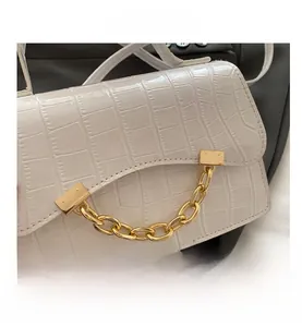 Detail of white crocodile texture handbag with chunky gold chain strap and flap closure