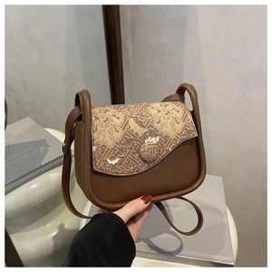Detail of vintage-style crossbody bag with intricate embroidery and brown faux leather finish