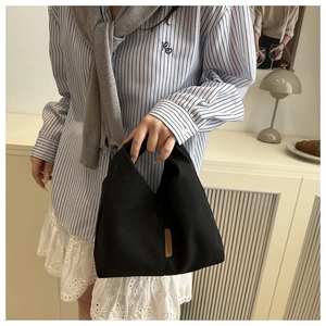 Détail d'un sac cabas en tissu noir avec étiquette en cuir marron et décor moderne
