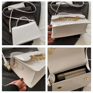 Close-up of white crocodile embossed mini bag with gold chain and magnetic buckle