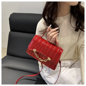 Détail du petit sac carré rouge à texture crocodile avec chaîne décorative dorée