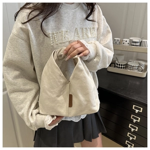 Gros plan du sac fourre-tout en velours côtelé beige avec l'étiquette en cuir marron