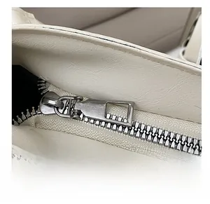 Detail showing the smooth silver metal zipper and black lining on white leather bag