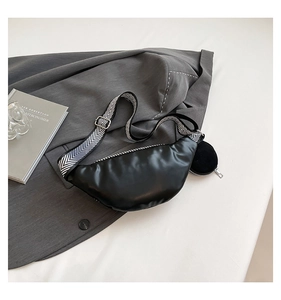 Detail of black crescent crossbody bag with woven herringbone strap and small coin purse