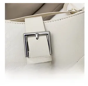 Detail of adjustable white leather strap and silver metal buckle on crescent bag
