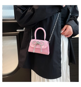 Detailed close-up of a pink patent leather mini bag with a sparkling silver bow and chain