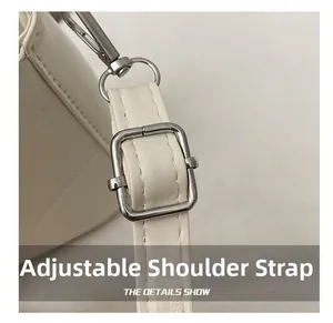 Detail showing adjustable faux leather shoulder strap with silver metal buckle on cream bag