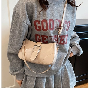 Detail view of a beige retro underarm bag featuring a large silver metal buckle strap