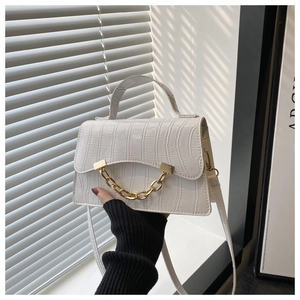 Détail macro d'un sac à main blanc gaufré crocodile avec chaîne décorative dorée
