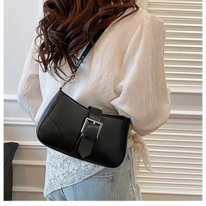Detail of a black synthetic leather crescent underarm bag with silver square metal buckle