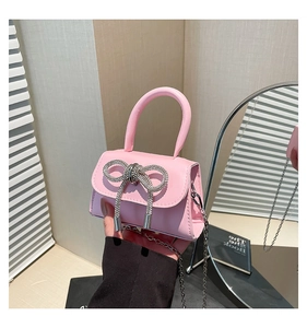Pink mini crossbody bag with a large rhinestone bow and silver chain strap