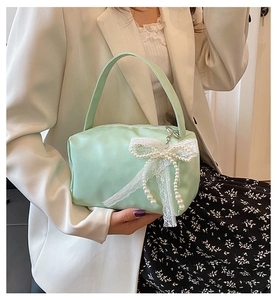 Close-up of mint green bag with white lace bow and elegant pearl tassel details