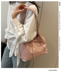 Detailed side view of a pink PU leather crescent shoulder bag with a ribbon bow decoration