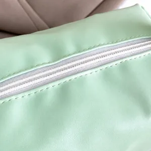 Makroaufnahme des weißen Reißverschlusses und der feinen Nähte der hellgrünen Tasche