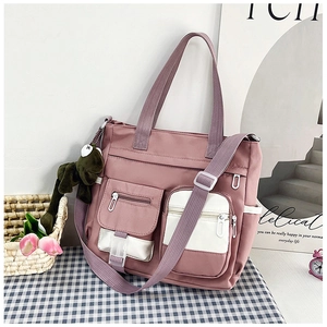Dettaglio della borsa tote in tela rosa multi-tasche con tracolla e ciondolo a rana