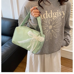 Close-up of mint green bag with pearl lace bow and smooth texture on sofa
