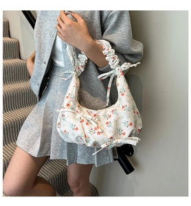 Close-up of floral underarm bag with pleated handle and side bow on model