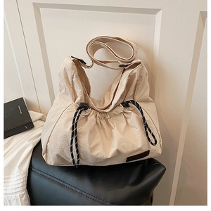 Detalle de bolso de nailon beige arrugado con cierre de cordón y cuerda trenzada
