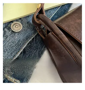 Close-up of brown PU leather saddle bag showing oily wax finish and fine stitching detail