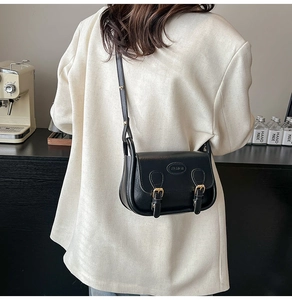 Close-up of a black PU leather saddle bag featuring double buckles and fashion embossing