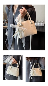 Detail der cremefarbenen Muscheltasche mit Spitzenschleife und Perlenanhänger aus Leder