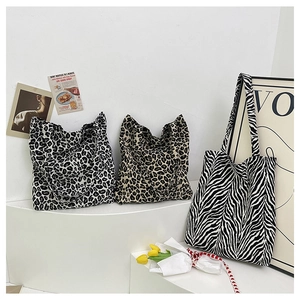 Tre borse tote in tela con stampe animalier leopardo e zebra su un supporto bianco