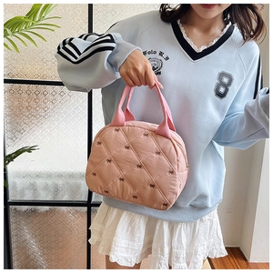 Détail du sac à main rose matelassé avec broderie nœud noir et tissu texturé bouffant