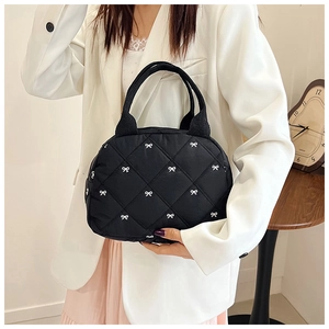 Gros plan détaillé du sac cabas matelassé noir avec motif nœuds blancs et anses rubans