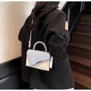 Détail d'un sac à main bicolore avec poignée tressée et rabat géométrique élégant
