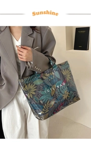 Detailed shot of a tropical print tote bag with clear PVC layer and top handles