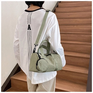Modelo con bolso cilíndrico Boston verde y un pequeño neceser redondo en la escalera