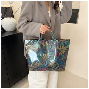 Detail of tropical leaf print tote bag with waterproof glossy finish and TOTE BAG text