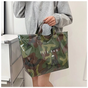 Detail of glossy camouflage tote bag featuring bold white TOTE BAG text on the front