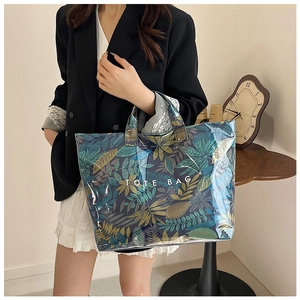 Detail of transparent tote bag featuring tropical leaf prints and sturdy carry handles